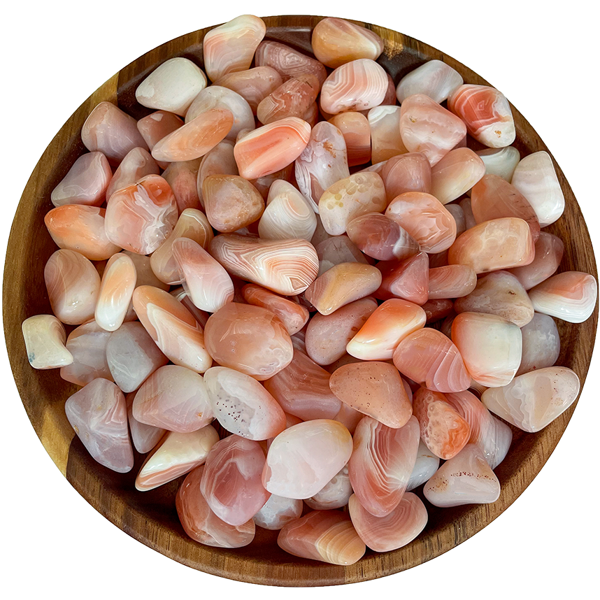 A pile of apricot agate stones on a wooden plate.