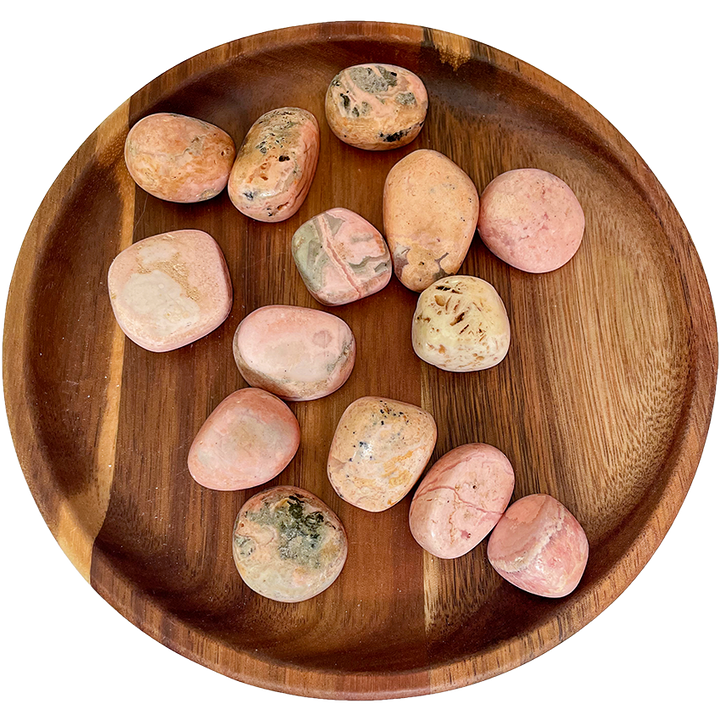 A collection of rhodochrosite crystals on a wooden plate.