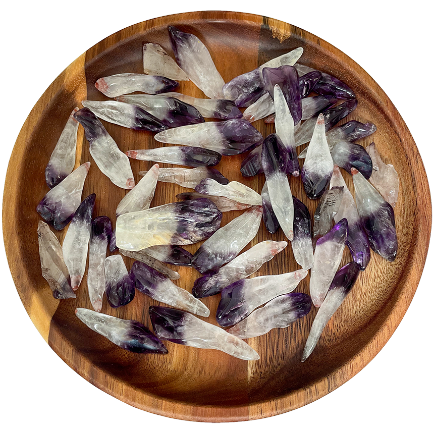 A collection of polished amethyst points on a wooden plate.