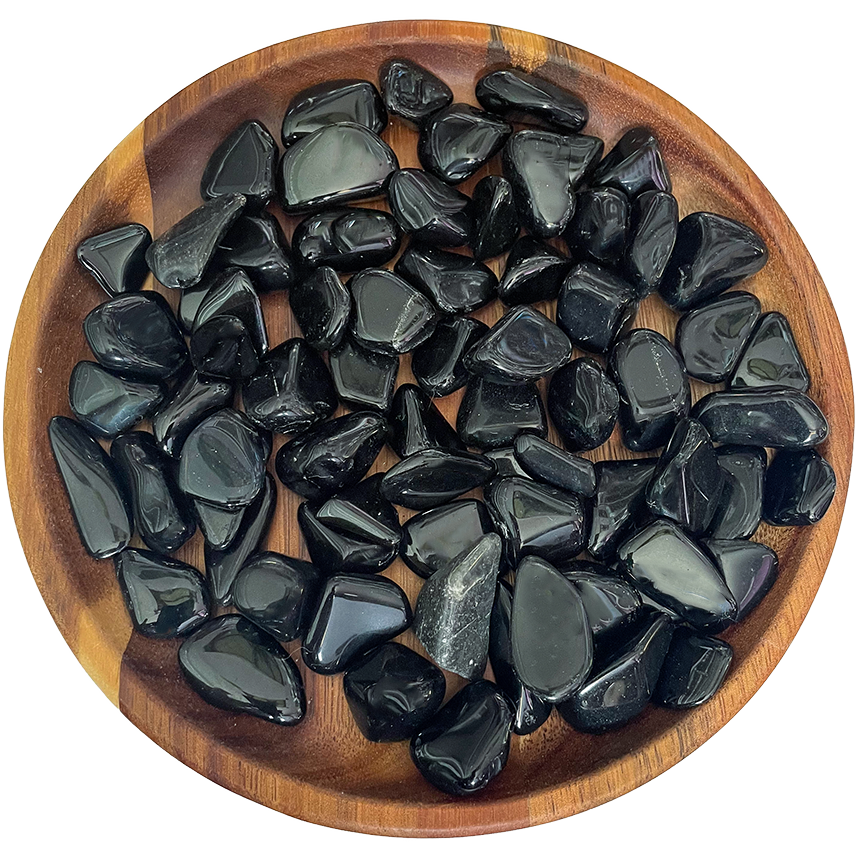 A collection of black obsidian crystals on a wooden plate.