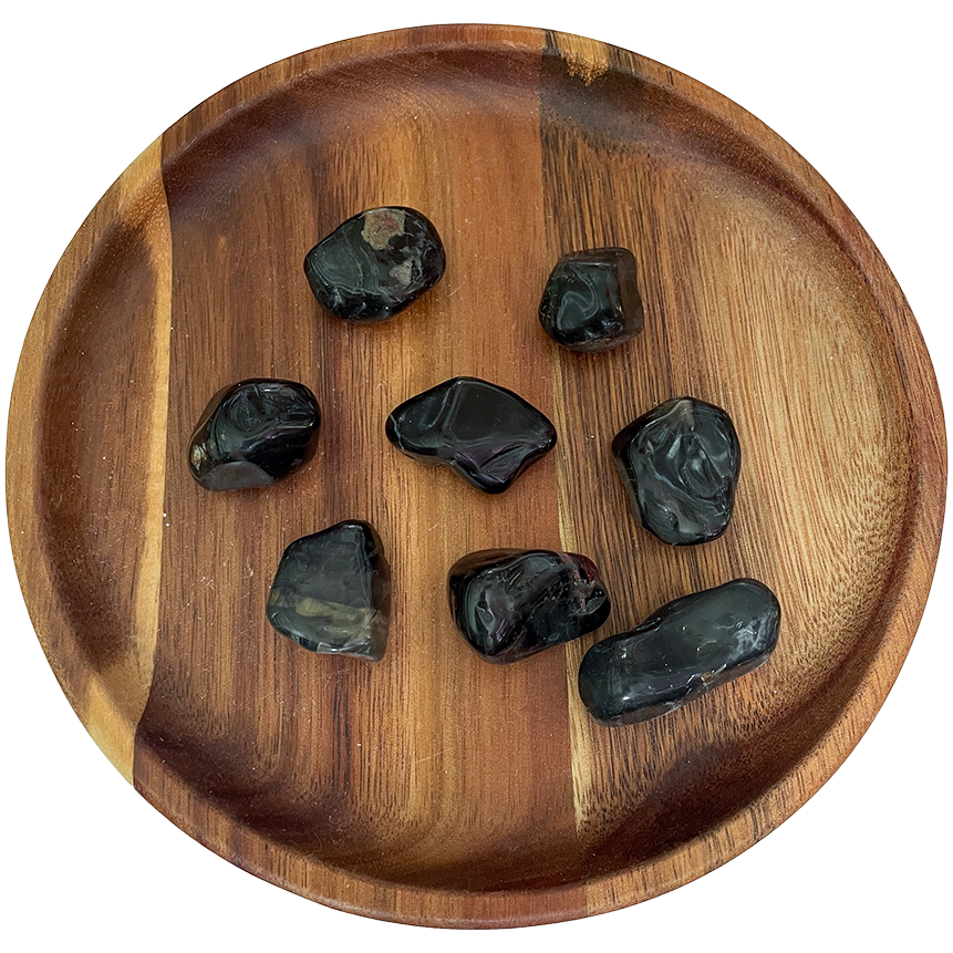 A collection of black onyx stones on a wooden plate.