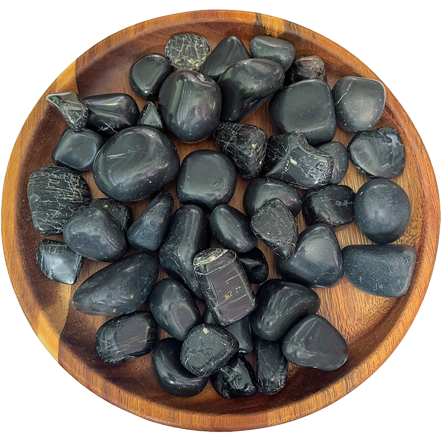 A collection of black tourmaline crystals on a wooden plate.