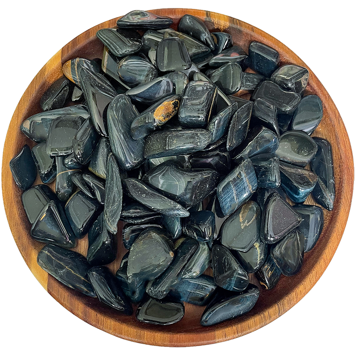 A collection of blue tiger's eye crystals on a wooden plate.