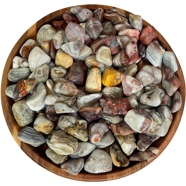 A collection of crazy lace agate stones on a wooden plate.