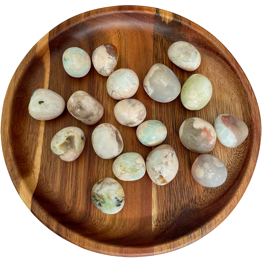 A collection of flower agate crystals on a wooden plate.