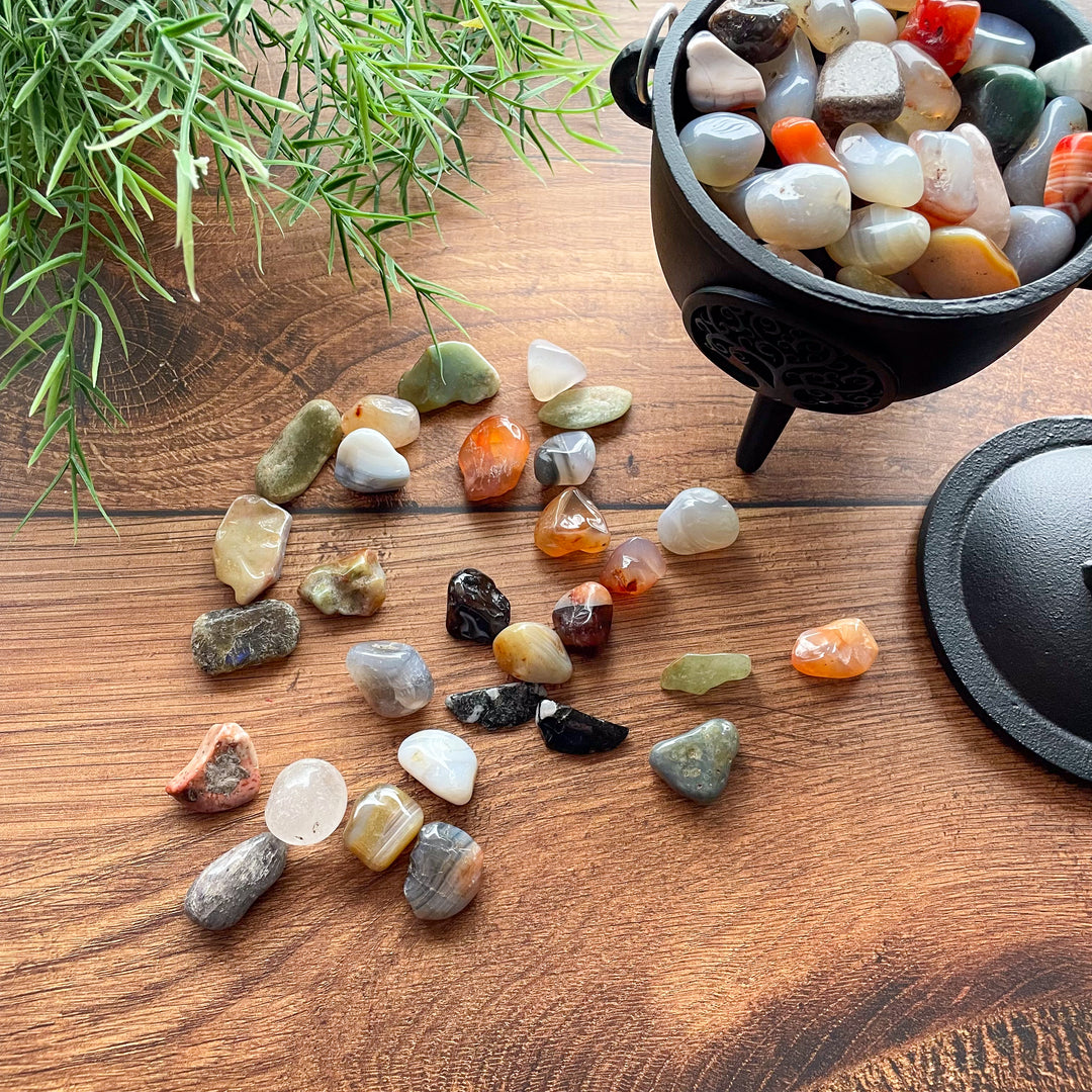Natural mixed agate stones laying on a wood background and in a black cauldron.