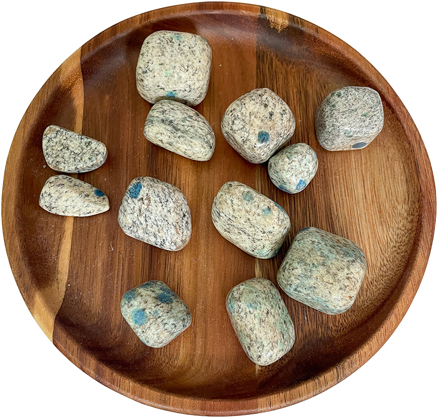 A collection of K2 jasper stones on a wooden plate.