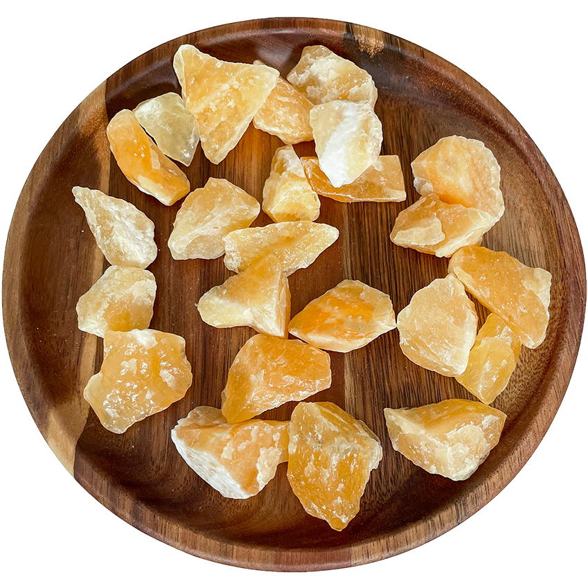 A collection of orange calcite stones on a wooden plate.