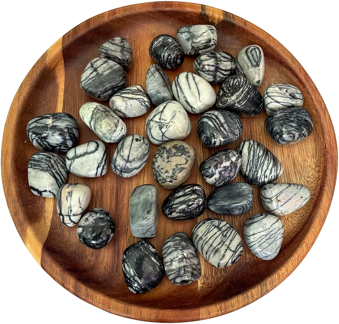 A collection of Picasso Jasper crystals on a wooden plate.