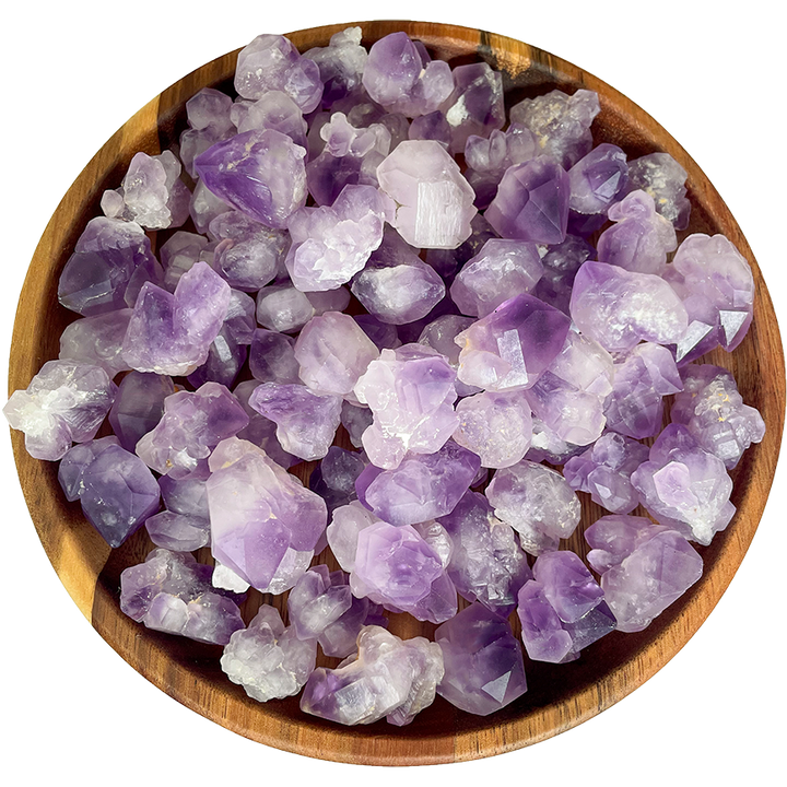 A collection of popcorn amethyst crystals on a wooden plate.