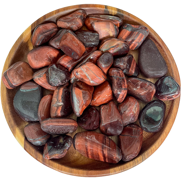 A collection of red tiger's eye stones on a wooden plate.
