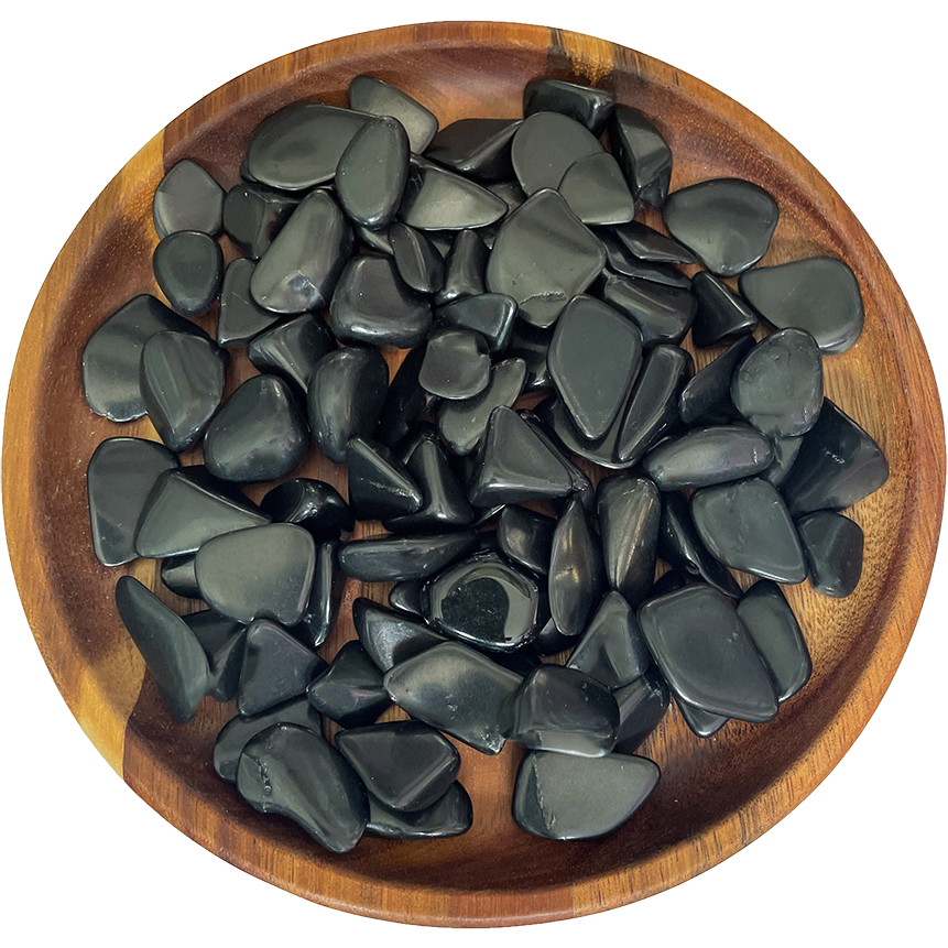 A collection of shungite crystals on a wooden plate.